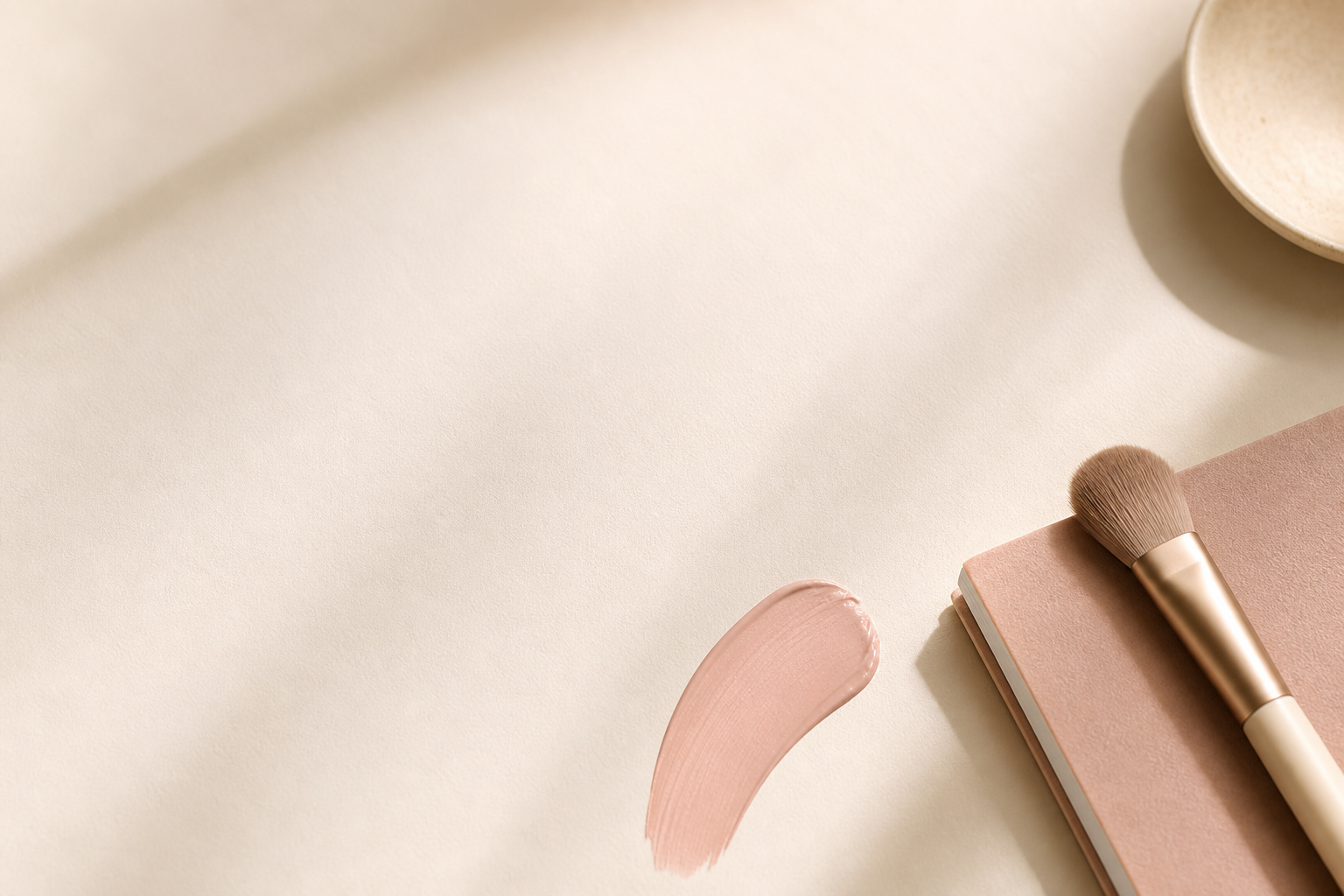 Soft pink beauty flatlay with a makeup brush and notebook